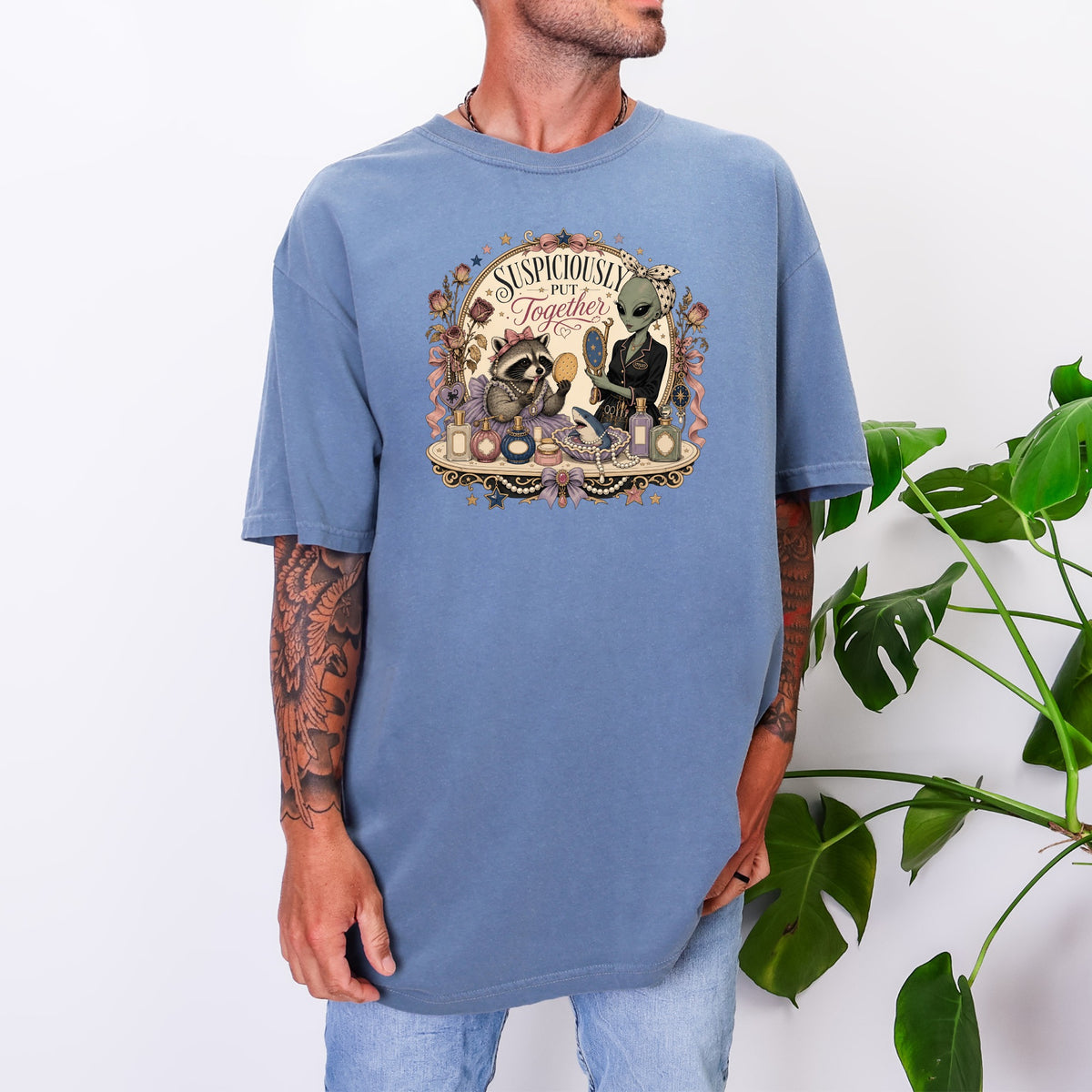 A person wearing a blue oversized t-shirt with a vintage graphic of an alien and raccoon.