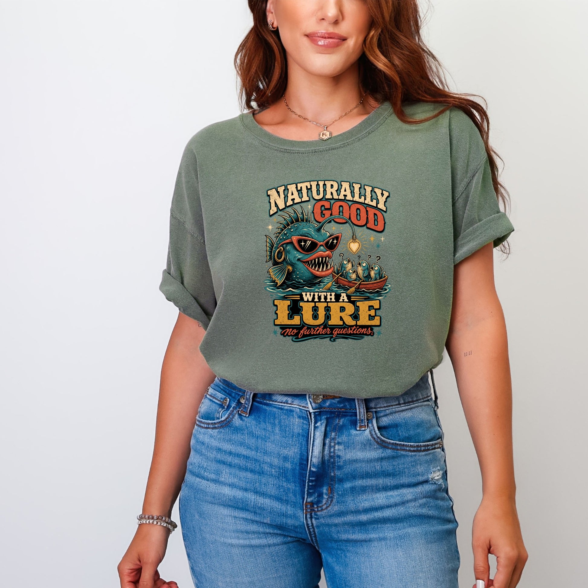 Green t-shirt graphic: anglerfish with sunglasses and text "Naturally Good With A Lure".