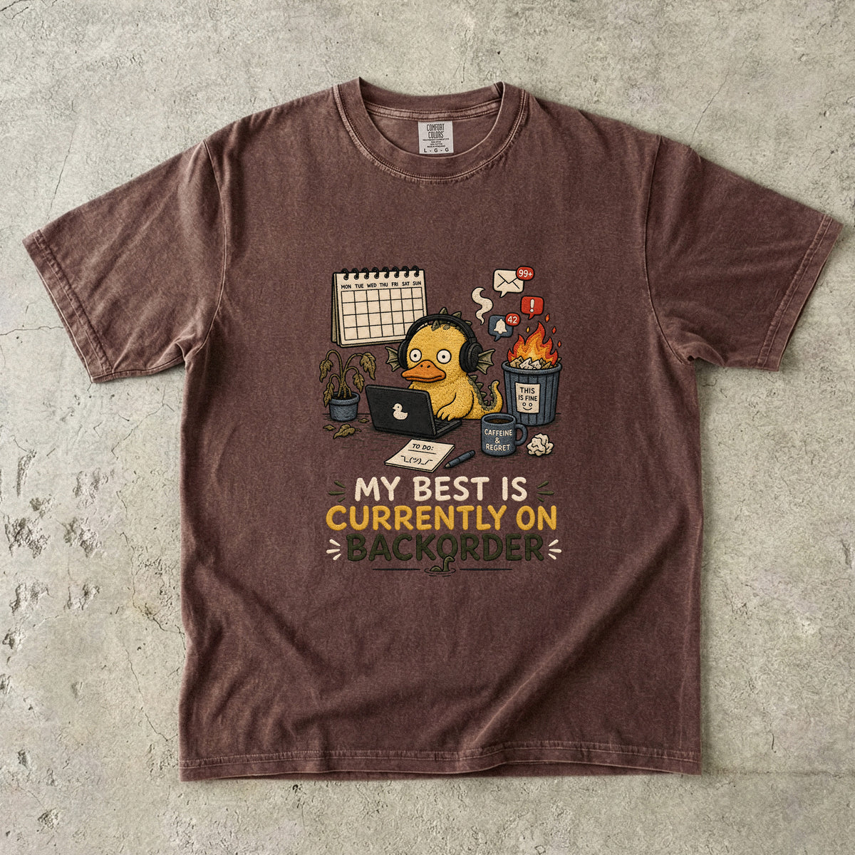 Brown t-shirt with graphic of overwhelmed duck character and text "My best is currently on backorder."
