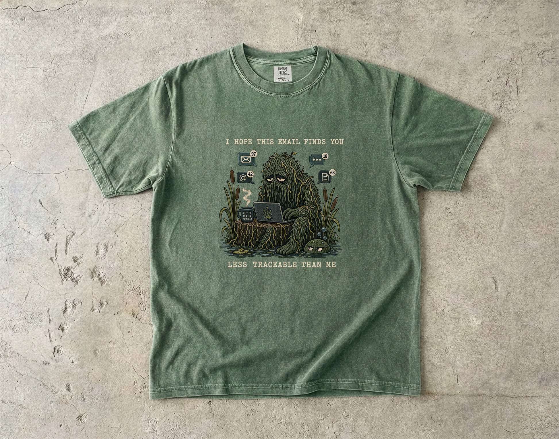 Green t-shirt with Bigfoot using a laptop and mug, text reads "I hope this email finds you less traceable than me."