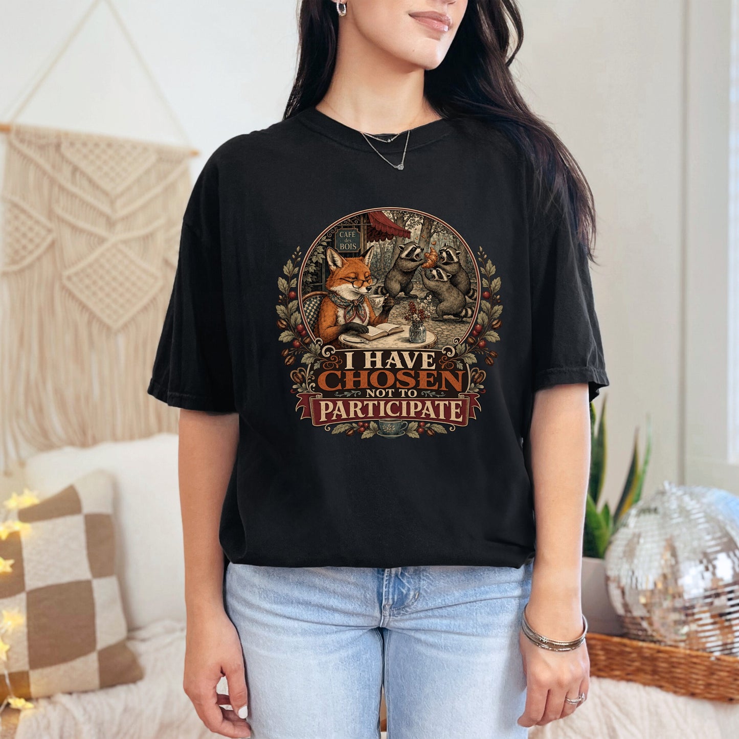 Black t-shirt with a circular graphic of a fox and raccoons at a cafe with text.