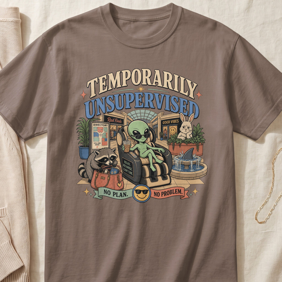 Brown t-shirt featuring a cartoon alien relaxing in a massage chair at a mall, with text stating Temporarily Unsupervised.