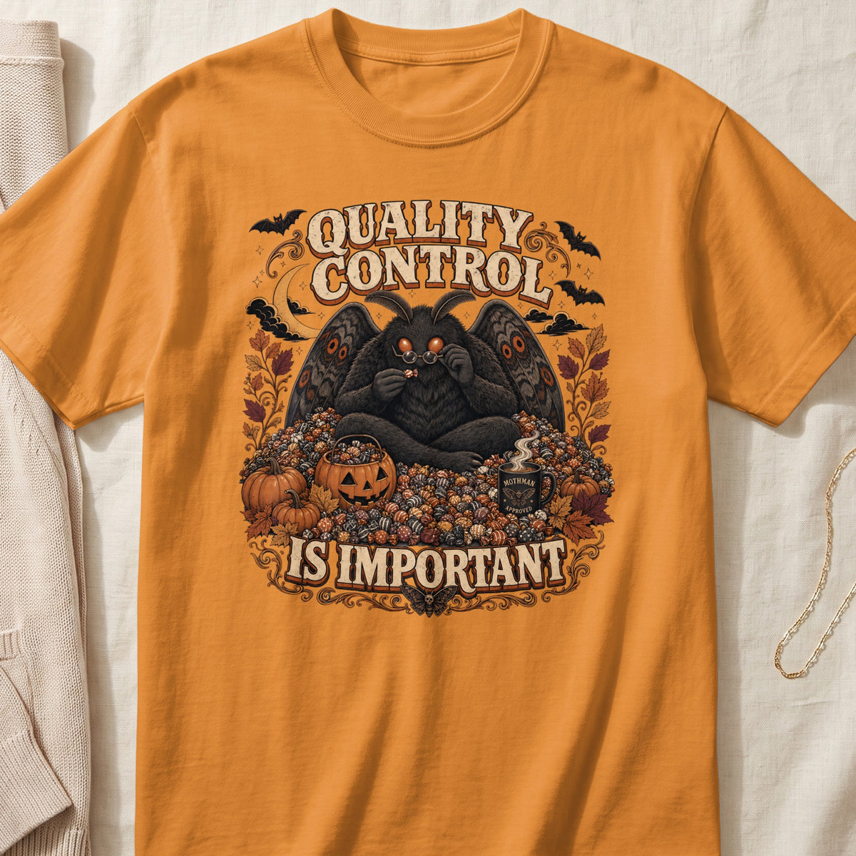 Orange t-shirt with Mothman artwork and text "QUALITY CONTROL IS IMPORTANT".