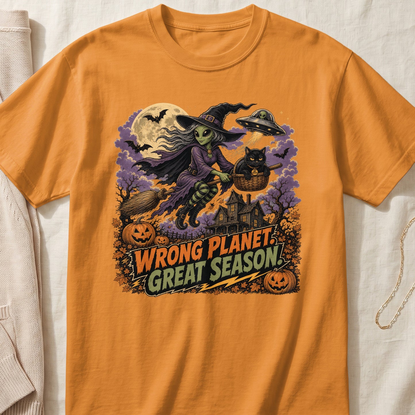 Orange t-shirt with Halloween graphic featuring an alien witch, black cat, and UFO.
