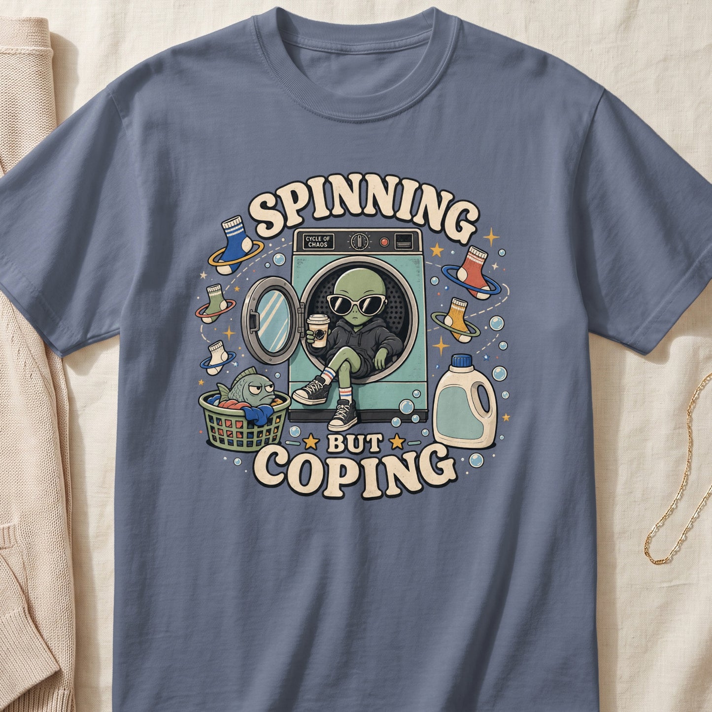 Alien wearing sunglasses sits in a washing machine with text "Spinning But Coping".