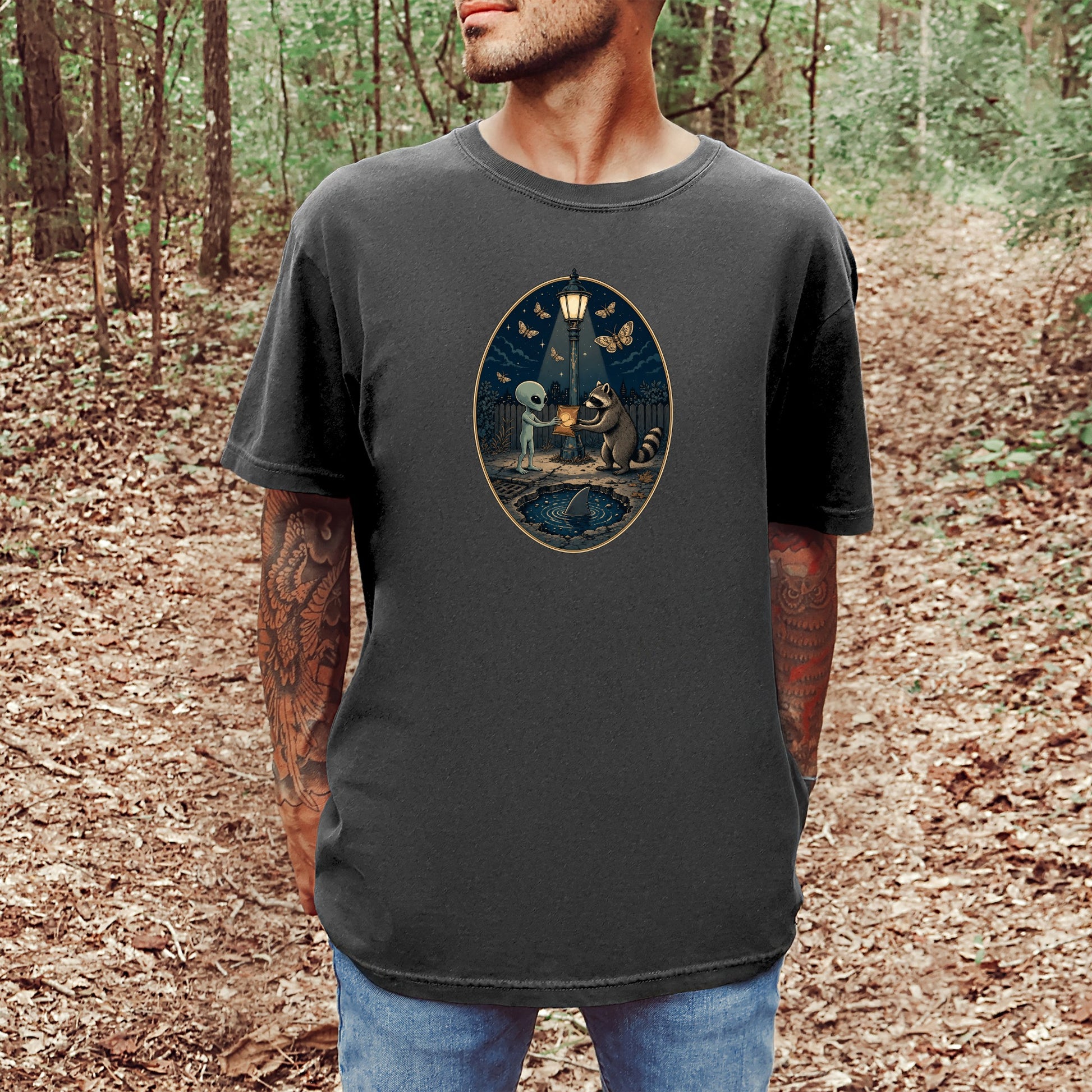T-shirt with alien and raccoon sharing a glowing object by a street lamp.