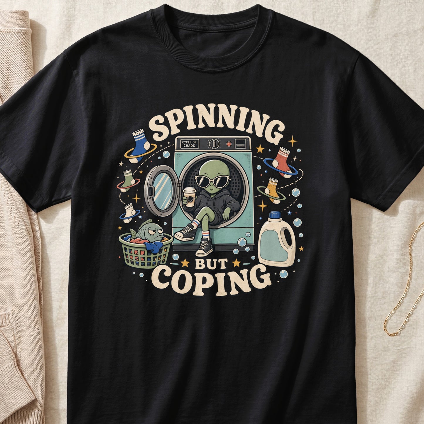 Black t-shirt with alien, washing machine, laundry basket, and text "Spinning But Coping".