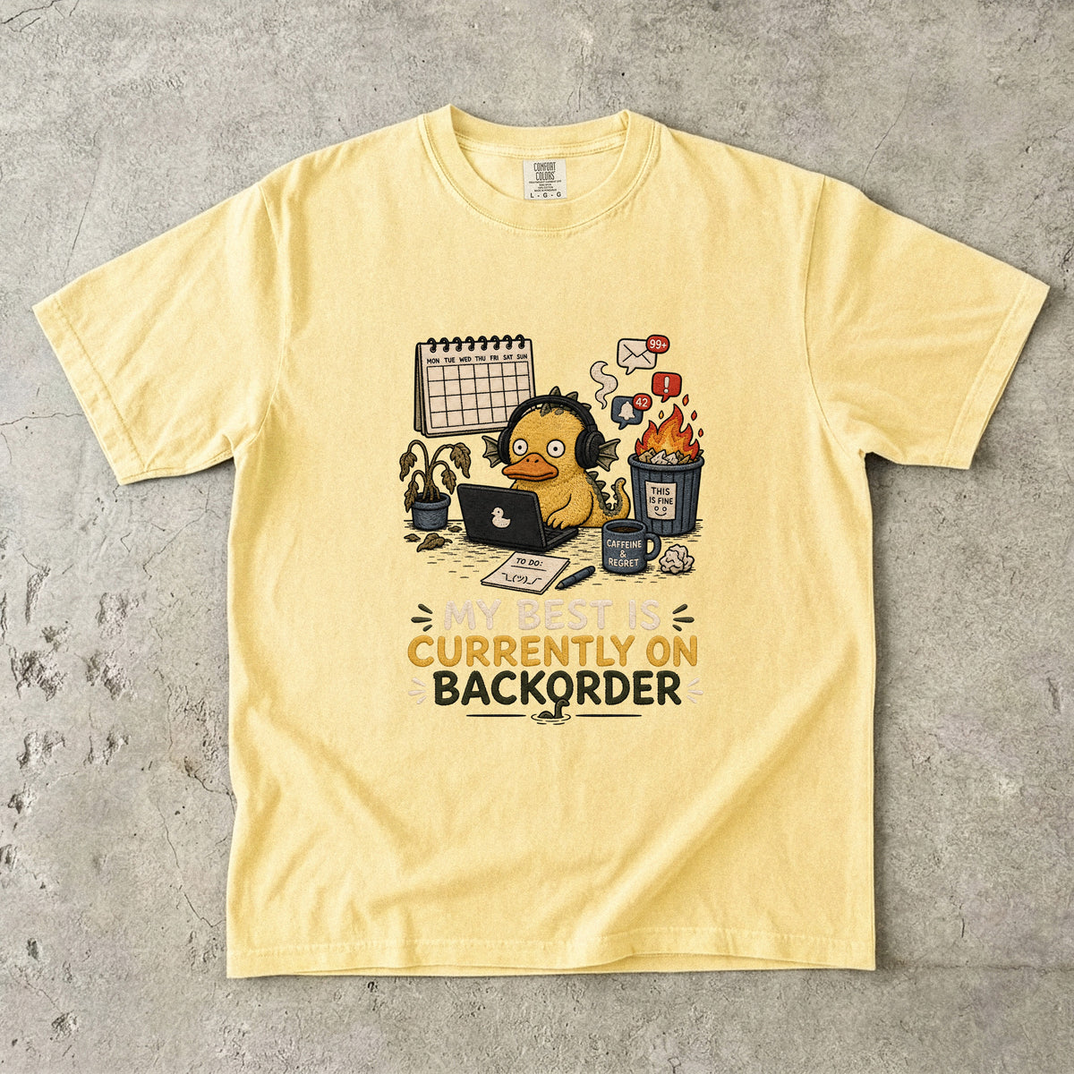 Yellow t-shirt with graphic of overwhelmed duck and text "MY BEST IS CURRENTLY ON BACKORDER".