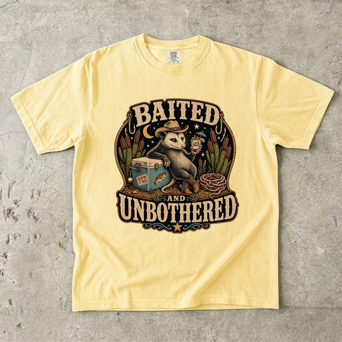 Yellow t-shirt with opossum graphic and text "BAITED AND UNBOTHERED".