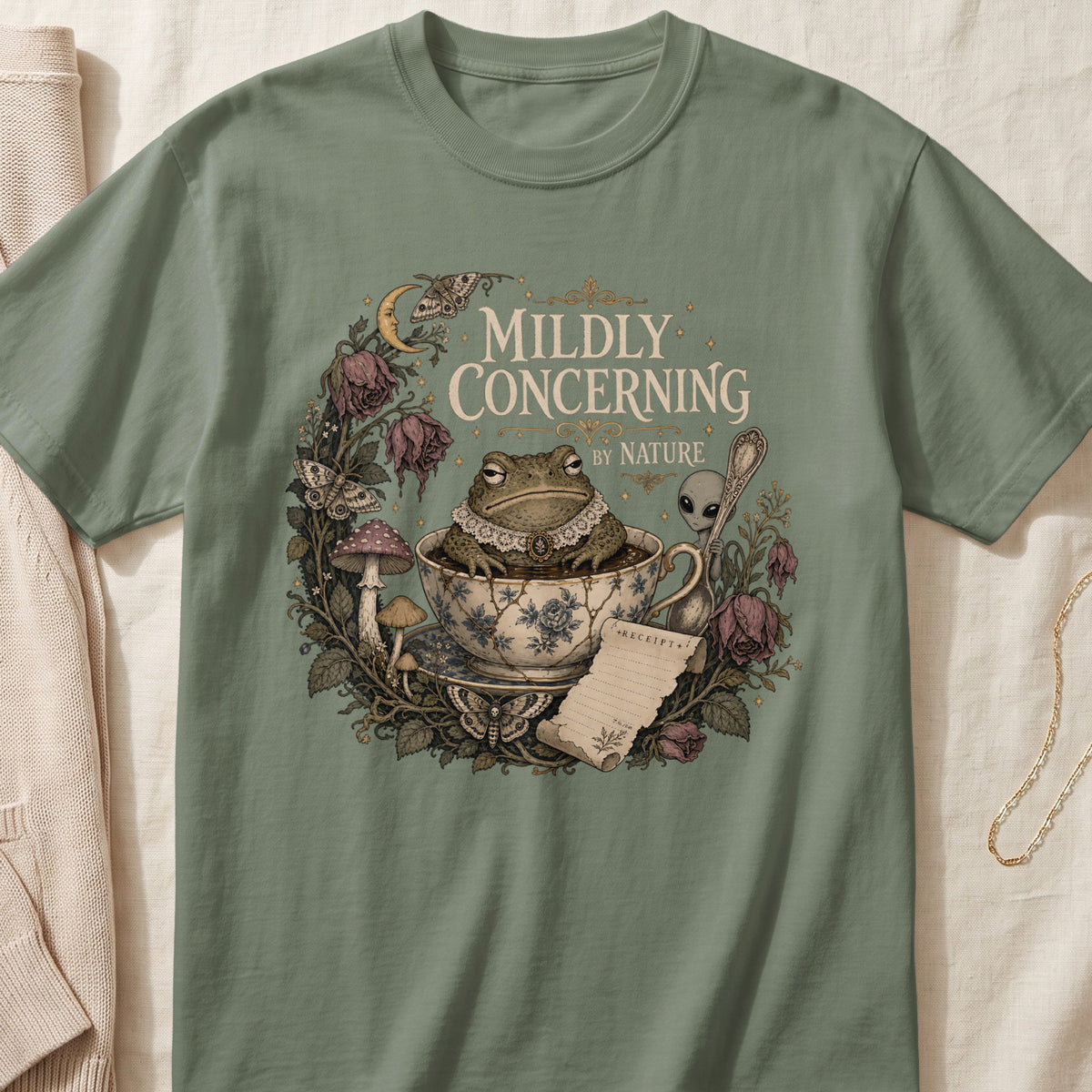 Toad in teacup with alien and text "Mildly Concerning By Nature" on t-shirt.