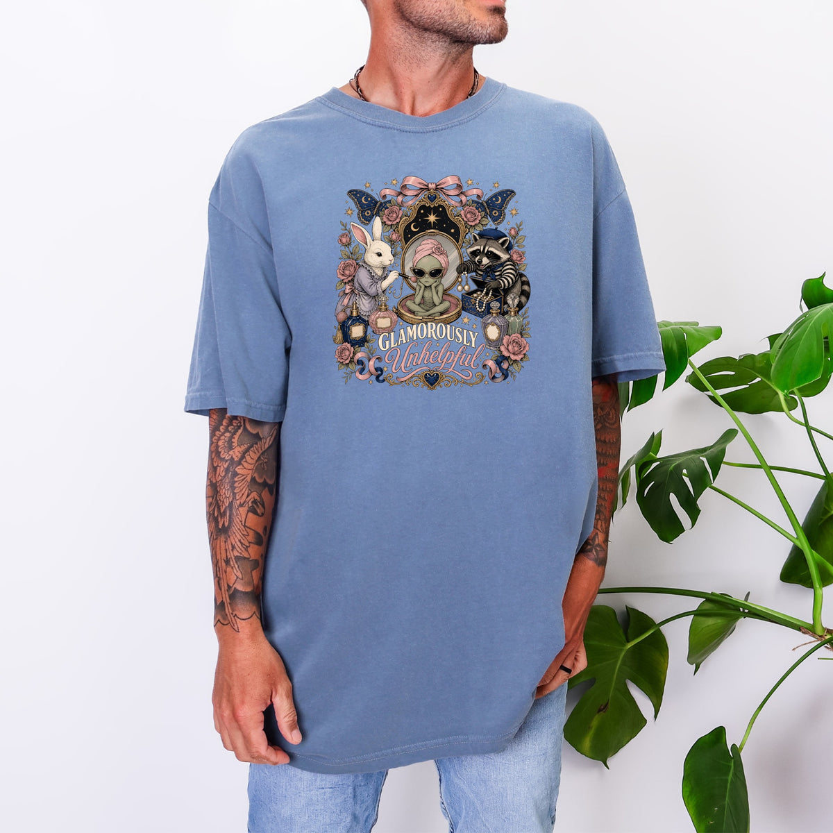 T-shirt graphic with alien, rabbit, raccoon, butterflies, and text "Glamorously Unhelpful".