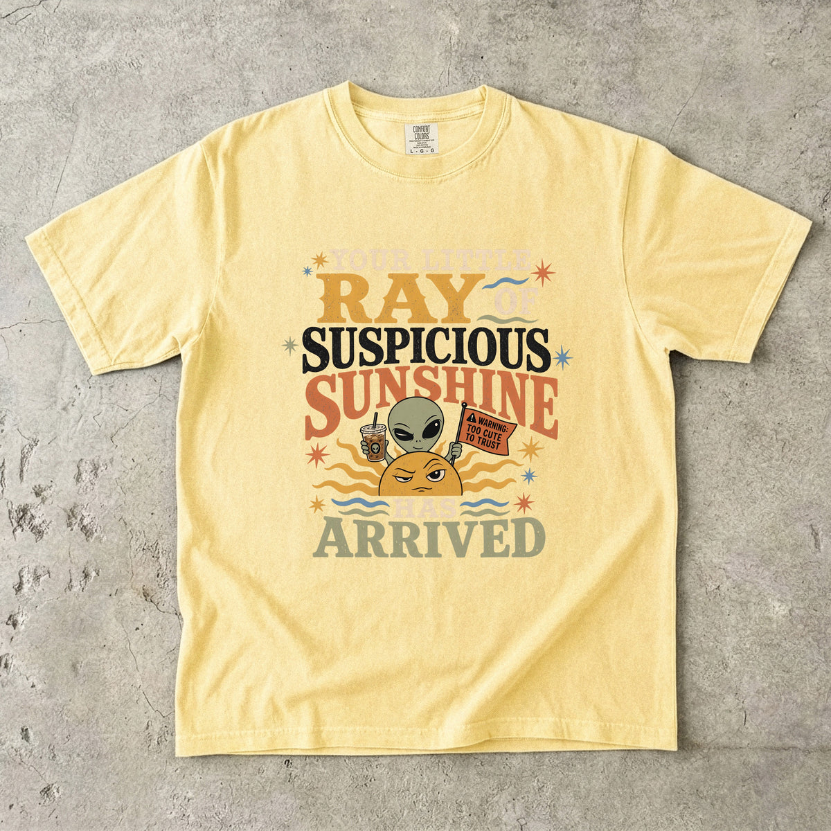 Yellow t-shirt with alien, sun, and coffee cup graphic reading "Ray of Suspicious Sunshine Has Arrived."