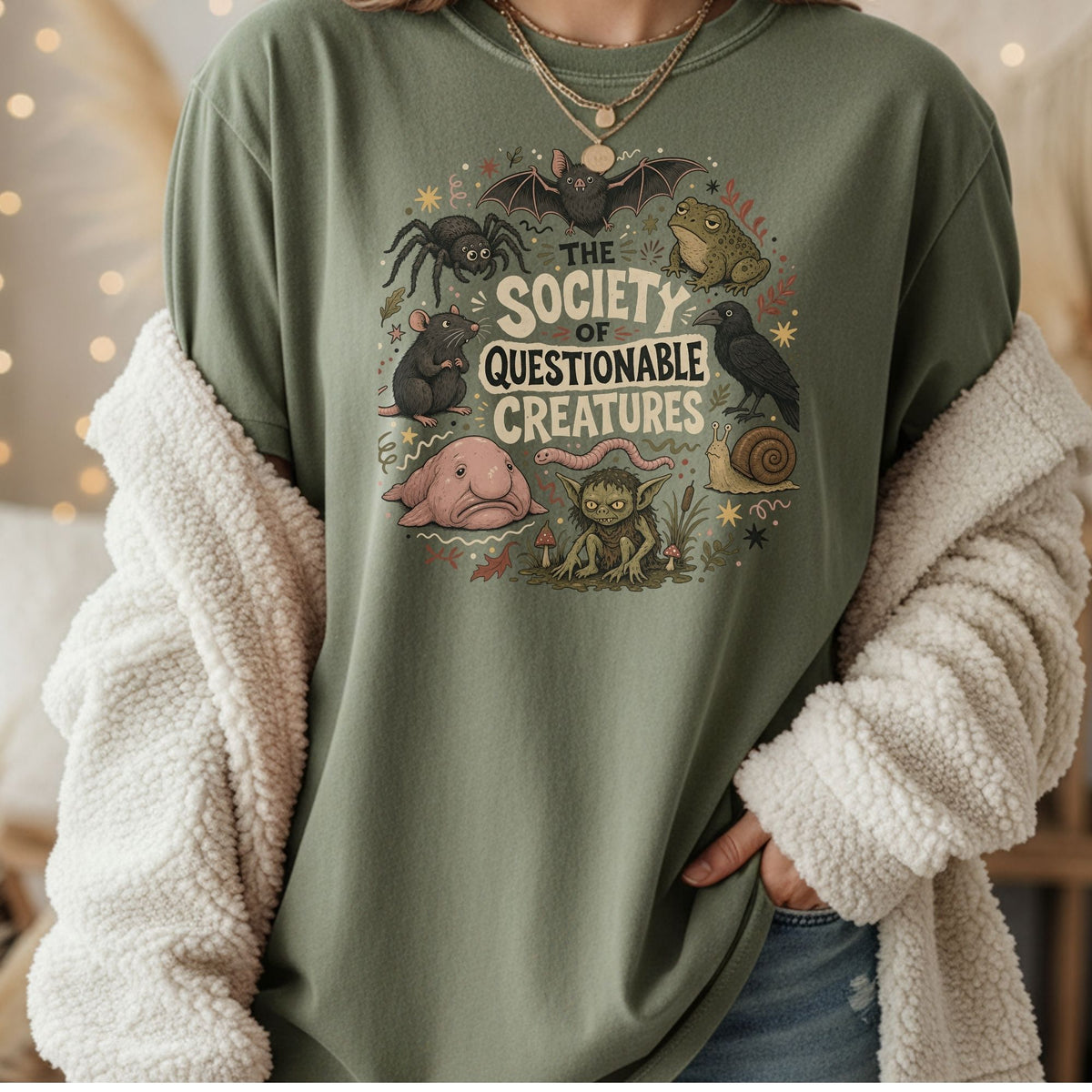 Green t-shirt with "The Society of Questionable Creatures" text and various creatures.