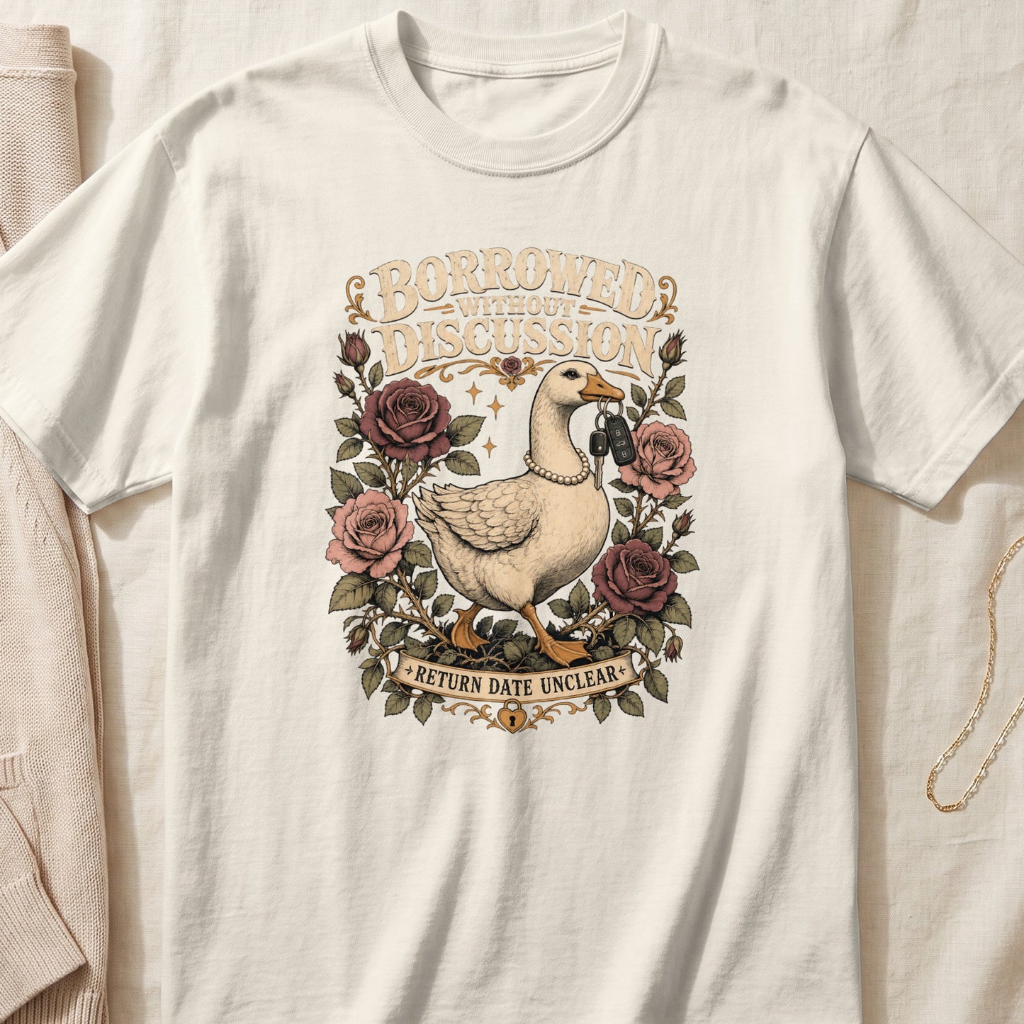 Cream t-shirt with a goose wearing pearls, holding keys, surrounded by roses and text.