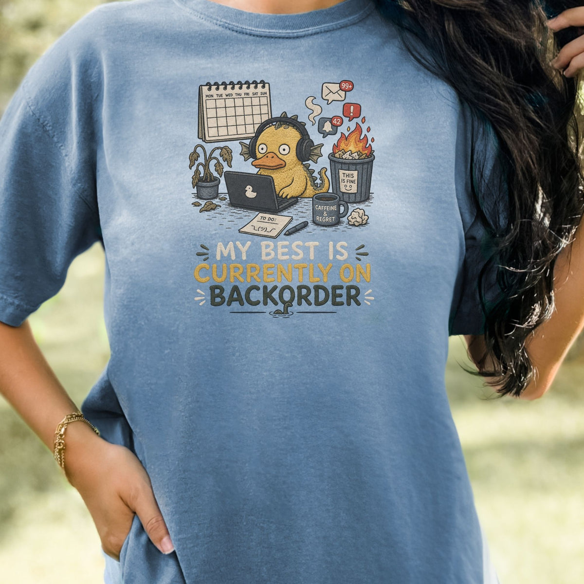 T-shirt graphic with stressed duck character and text "MY BEST IS CURRENTLY ON BACKORDER".