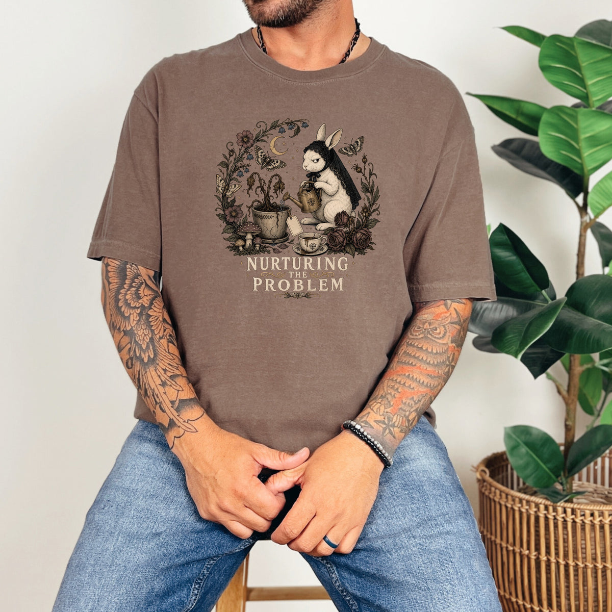 T-shirt graphic of rabbit watering a plant with text "NURTURING THE PROBLEM".