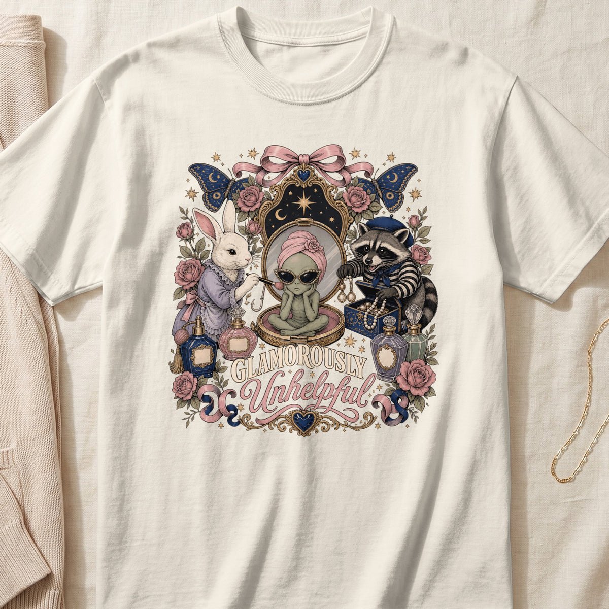 White t-shirt graphic with alien, rabbit, raccoon, perfumes, and "Glamorously Unhelpful" text.