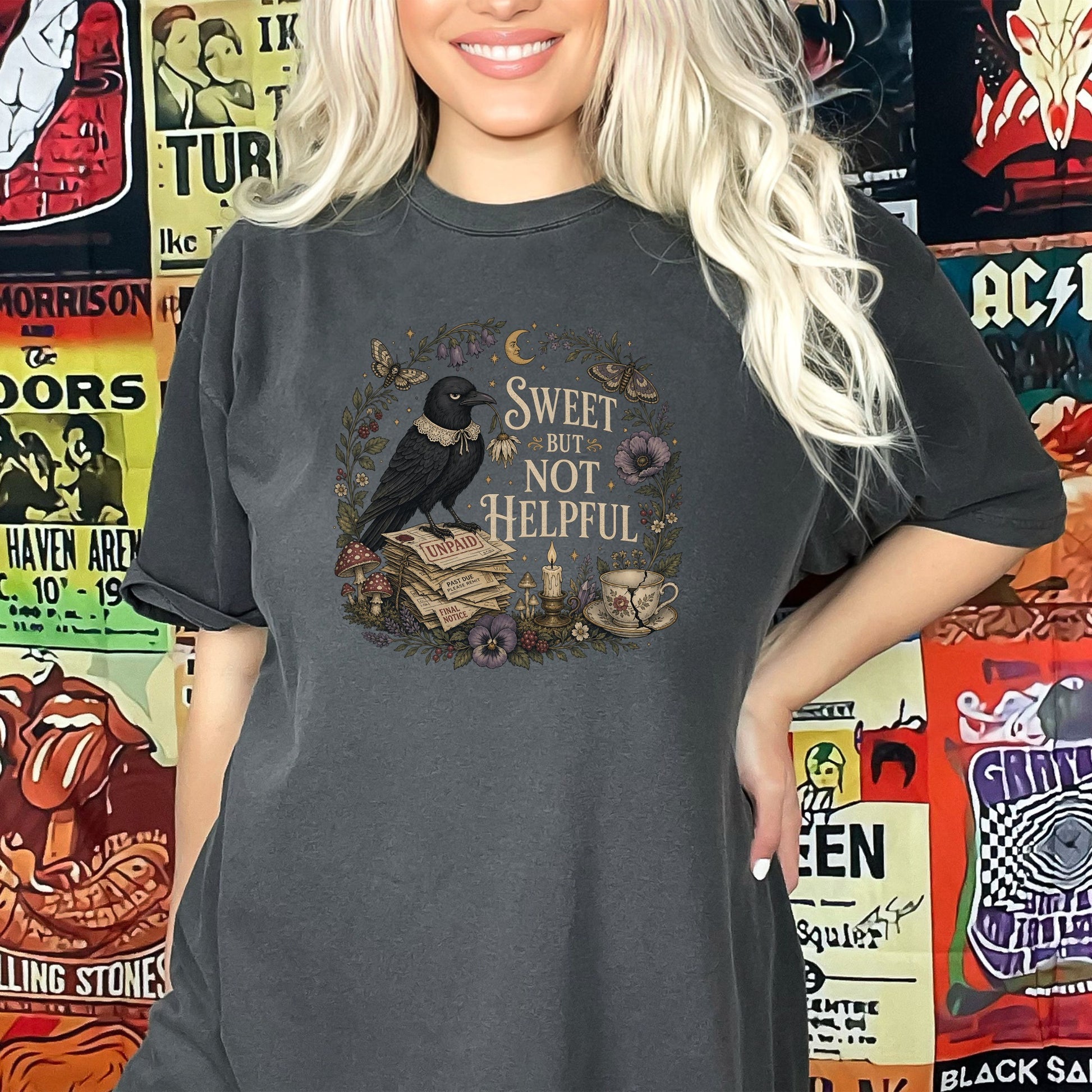 Dark grey t-shirt with crow on stacked papers, text "SWEET BUT NOT HELPFUL".