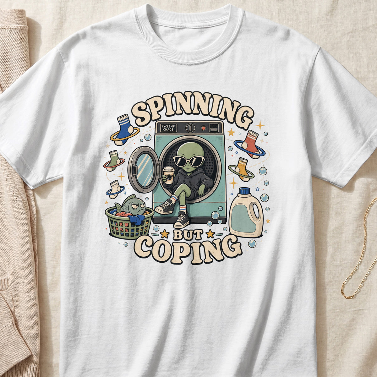 Alien in washing machine, "Spinning but Coping" text, with laundry basket and detergent bottle.