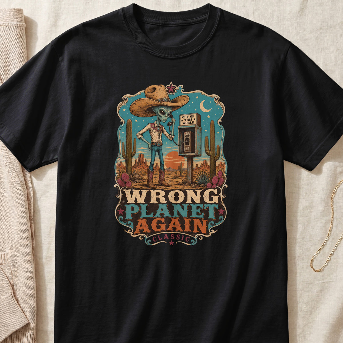 Alien in cowboy hat on a phone booth in a desert with text "Wrong Planet Again."